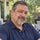 Candid portrait of Carlos V., a 50-year-old man smiling on his back patio wearing a button-down shirt tucked cleanly into his