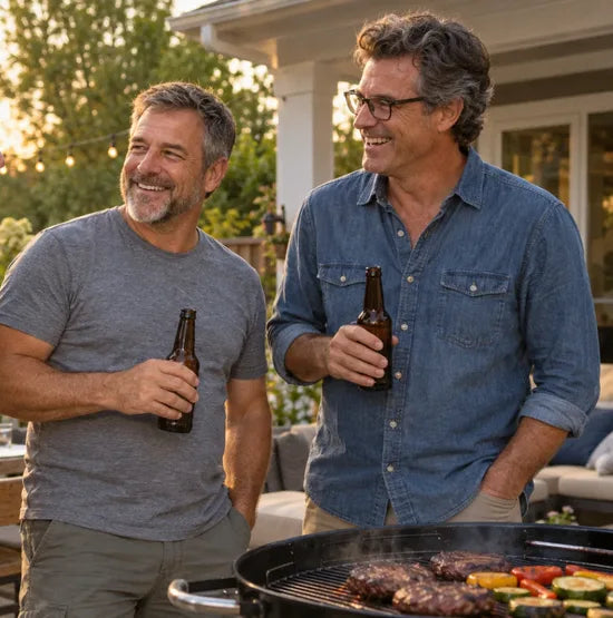 Friends with cold beers next to steaks on a backyard grill